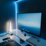 A sleek and modern workspace setup featuring a desktop monitor, keyboard, and LED lighting.