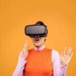 Woman immersed in virtual reality, wearing a VR headset against a vibrant orange background.